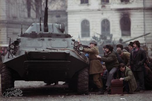 Бухарест, 23 декабря 1989 года. Солдаты и помогающие им гражданские лица прячутся за бронетехникой. (Фотография: Corbis/Scanpix)